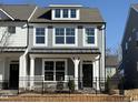 Charming two-story home with gray siding, black door, black metal fence, and professionally landscaped yard at 476 Traditions Grande Blvd # 33, Wake Forest, NC 27587