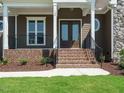 Inviting front porch with brick steps and iron railings on a home with stone accents at 142 Batten Hill Ln, Selma, NC 27576