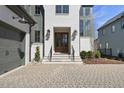 Elegant entryway with a wood front door, stone steps, black railings, and a paved driveway at 3410 Bradley Pl, Raleigh, NC 27607