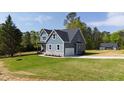 Blue two-story home with an attached garage, green lawn, and lovely landscaping features at 123 Wichita Way, Louisburg, NC 27549
