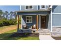 Inviting front porch with comfortable seating and stone accents on the exterior with dark wood door at 123 Wichita Way, Louisburg, NC 27549