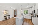 Bright kitchen features white cabinetry, granite countertops, island, and stainless appliances at 123 Wichita Way, Louisburg, NC 27549