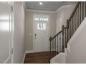 Bright foyer featuring hardwood floors, staircase with dark metal railing, and a white front door at 1825 Hinesley Dr, Durham, NC 27703
