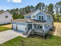 Two-story home featuring a manicured lawn, a three car garage, and a charming front porch at 155 Shelby Meadow Ln, Angier, NC 27501