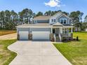 Two-story home featuring a manicured lawn, a three car garage, and a charming front porch at 155 Shelby Meadow Ln, Angier, NC 27501