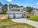 Two-story home featuring a manicured lawn, a three car garage, and a charming front porch at 155 Shelby Meadow Ln, Angier, NC 27501