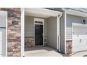 Covered entryway with stone accents and a black front door with sidelights and a transom window at 1827 Hinesley Dr, Durham, NC 27703