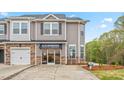 Townhome with brick accents and neutral siding, showcasing a covered entrance and a well-maintained lawn at 1831 Hinesley Dr, Durham, NC 27703
