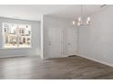 An airy living area with neutral walls, gray wood floors, and a charming light fixture with backyard view at 281 Chesapeake Commons St # 95, Garner, NC 27529