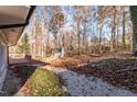 View of a wooded backyard with a wooden deck and a gravel path at 6512 Johnsdale Rd, Raleigh, NC 27615