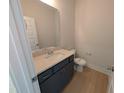 Half bathroom with dark vanity and light wood-look tile floor at 8 Steppe Way, Garner, NC 27529