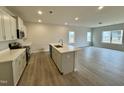 Bright, open kitchen featuring an island, quartz counters, stainless appliances, and hardwood floors at 108 Commons Circle # 228, Clayton, NC 27520