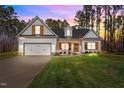 White two-story house with a front porch and landscaping at dusk at 151 Ottawa Dr, Louisburg, NC 27549