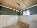 An elegant dining room showcases wood floors, ceiling, wainscoting, complemented by an ornate, linear chandelier at 1721 Burnette Garden Path, Raleigh, NC 27612