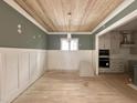 A dining area featuring wood floors, wainscoting, a wood ceiling, and seamlessly connects to the modern kitchen at 1721 Burnette Garden Path, Raleigh, NC 27612