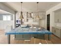 An expansive kitchen design with modern, gray cabinets, gold pendant lights, and a spacious island, perfect for cooking at 1721 Burnette Garden Path, Raleigh, NC 27612