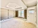 Living room with decorative paneled walls, large window, tray ceiling, and unfinished floors at 2624 Silver Gate Ct, Wake Forest, NC 27587