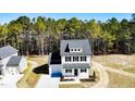 Aerial view of a modern farmhouse featuring a well-manicured lawn and proximity to a lush forest at 806 Roberts Rd, Sanford, NC 27332