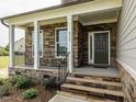 Inviting front porch with stone accents, black iron railings, and an elegant entryway at 8305 Cannon Grove Dr, Willow Springs, NC 27592