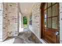 View of the front porch, featuring brick siding, stone floors, an arched entryway, and a wooden door at 3302.5 Hall Pl, Raleigh, NC 27607