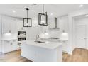 Modern kitchen with white cabinets, stainless steel appliances, an island, and stylish pendant lights at 800 Heathered Farm Way, Apex, NC 27523