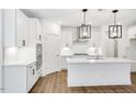 Bright kitchen featuring an island, stainless steel appliances, white cabinets, and modern lighting fixtures at 800 Heathered Farm Way, Apex, NC 27523