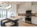 Stylish kitchen featuring an island with bar seating, stainless steel appliances, and contemporary lighting at 120 Mosaic Blvd # 307, Pittsboro, NC 27312
