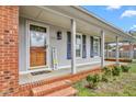 Inviting front porch with brick steps, charming decor, and gray siding at 2169 Northcrest Dr, Elon, NC 27244