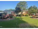 Quaint brick home featuring a well-maintained lawn with landscaped garden beds at 229 Davis Mill Rd, Selma, NC 27576