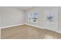 Bright, empty living space with wood-look flooring, a large window, and a white door at 107 Wilderness Ct, Mebane, NC 27302