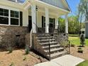 Inviting front porch with stone accents and black iron railings at 19 Covey Rise Way, Lillington, NC 27546