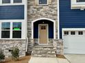 View of the front entrance with stone accents, including the door, windows, and attached garage at 222 Grand Griffon Way, Lillington, NC 27546