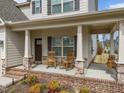 Inviting front porch featuring classic rocking chairs and swing seating, perfect for relaxing, with beautiful brick accents at 316 Spruce Pine Trl, Knightdale, NC 27545