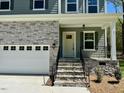Charming home exterior showcasing stone accents, a covered porch, and a two-car garage at 45 Covey Rise Way, Lillington, NC 27546