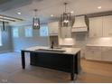 Bright kitchen featuring white cabinets, a large island with a sink, and modern pendant lighting at 136 Bar Code Ct, Wendell, NC 27591