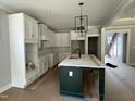 Bright kitchen with white cabinets, modern light fixtures, and large dark island at 136 Bar Code Ct, Wendell, NC 27591