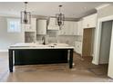 Bright kitchen with white cabinets, modern light fixtures, and large dark island at 136 Bar Code Ct, Wendell, NC 27591