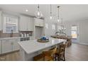 Bright kitchen with white cabinetry, a large island with seating, pendant lighting, and an adjacent dining area at 2317 Forsythia Trl, Fuquay Varina, NC 27526