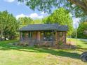 Inviting brick home with a covered porch, complete with hanging flower baskets and a tree swing in the yard at 320 W Orange St, Hillsborough, NC 27278
