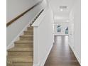 Inviting hallway with hardwood floors leading to a carpeted staircase and a bright living area at 520 Eversden Dr, Zebulon, NC 27597