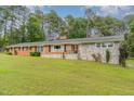 Attractive brick and stone home with a green front lawn, set against a backdrop of lush trees at 129 Jeffress Dr, Louisburg, NC 27549