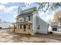 A charming gray two-story home featuring a welcoming porch, a black front door, and a detached garage at 182 Sierra Trl, Spring Lake, NC 28390