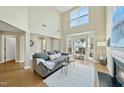 Bright living room with high ceilings, large windows, fireplace, and cozy gray sofa at 418 Bergen Ave, Apex, NC 27502