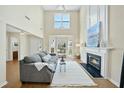 Bright living room with high ceilings, fireplace, and cozy gray sofa at 418 Bergen Ave, Apex, NC 27502