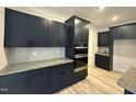 Modern kitchen featuring navy cabinets, stainless steel appliances, and stone countertops at 200 Ironwood Lot 39 Blvd, Youngsville, NC 27596