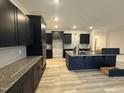 Modern kitchen featuring navy cabinets, an island, stainless appliances, and stone countertops at 200 Ironwood Lot 39 Blvd, Youngsville, NC 27596