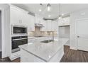 Modern kitchen featuring white cabinets, stainless steel appliances, and a marble countertop island at 11548 Helmond Way # 118, Raleigh, NC 27617