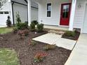 Landscaped front yard featuring a bright red front door and newly installed mulch and blooming flowers at 105 Windchime Ct, Fuquay Varina, NC 27526