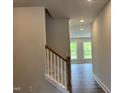 Hallway with wood-look flooring that has a staircase with painted risers and a stained railing at 105 Windchime Ct, Fuquay Varina, NC 27526