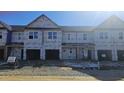 New townhomes under construction with visible housewrap, windows, and garage doors awaiting final finishes at 3858 Well Fleet Drive, Willow Springs, NC 27592